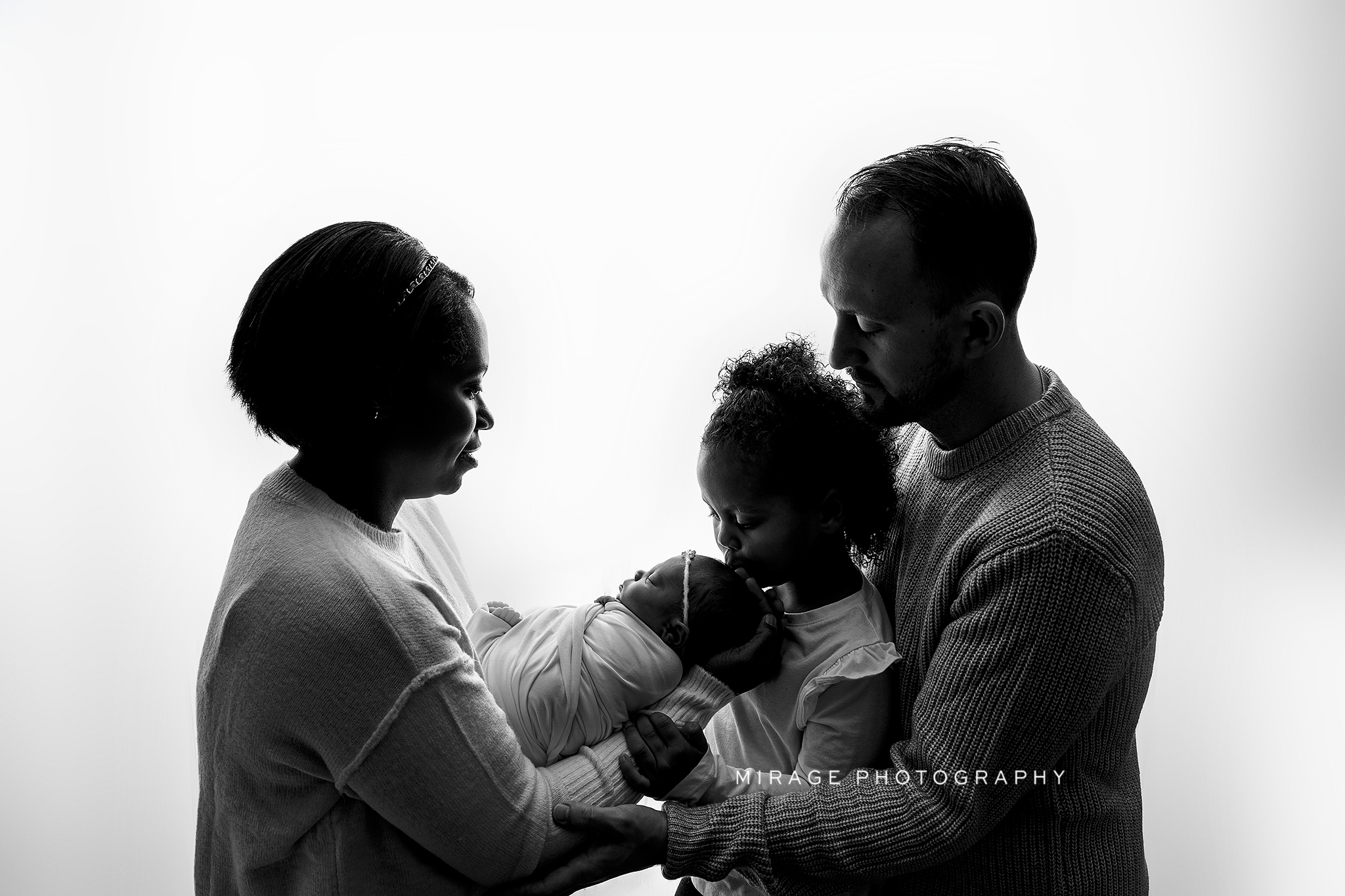 Parents posed cheek-to-cheek with baby in center.
