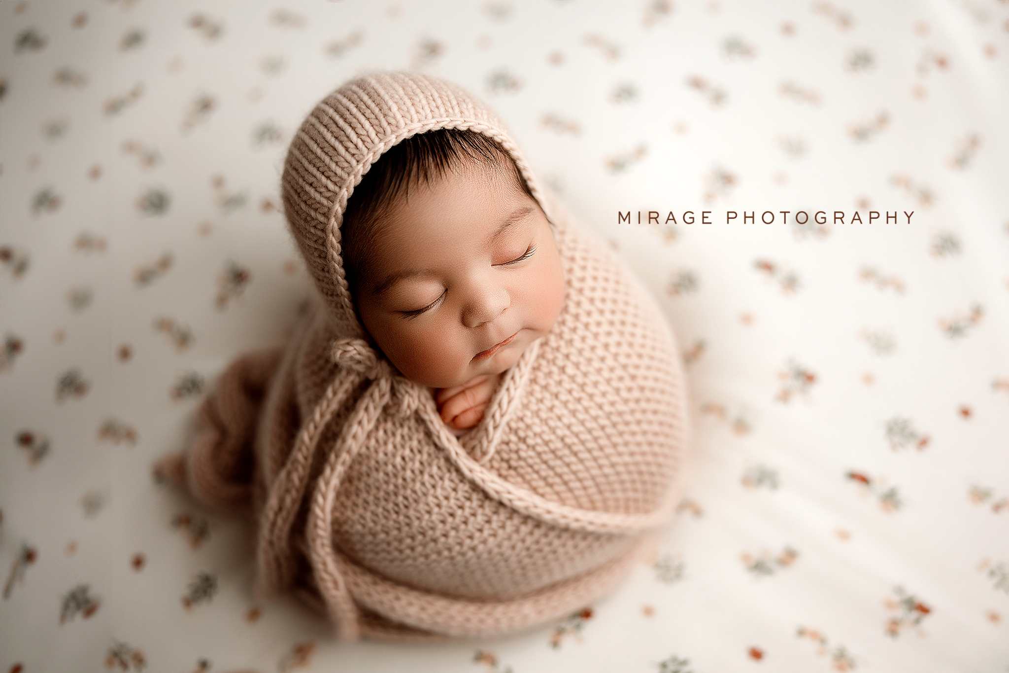 Sleeping newborn wrapped in neutral tones during a studio portrait in Fowlerville Michigan