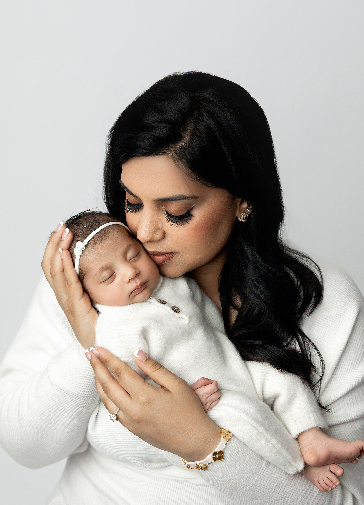 Guided family pose with newborn swaddled in neutral wrap.