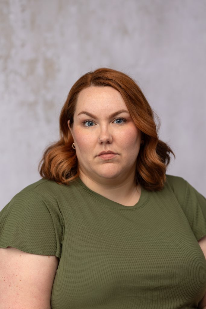 Professional headshot of a woman with red hair wearing a green top, photographed by Mirage Photography in Fowlerville, Michigan.