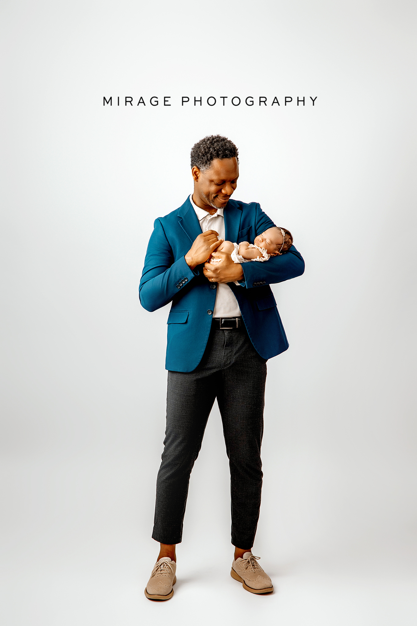 Dad in simple neutral shirt holding newborn.