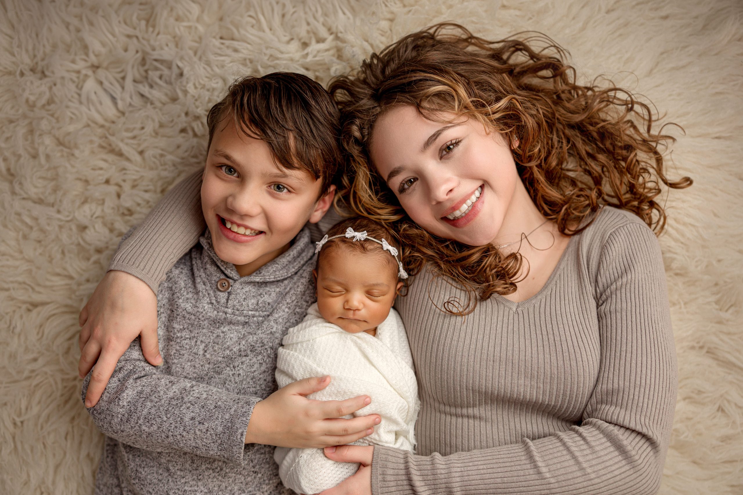 Dad cradling baby while mom’s hands frame the moment.
