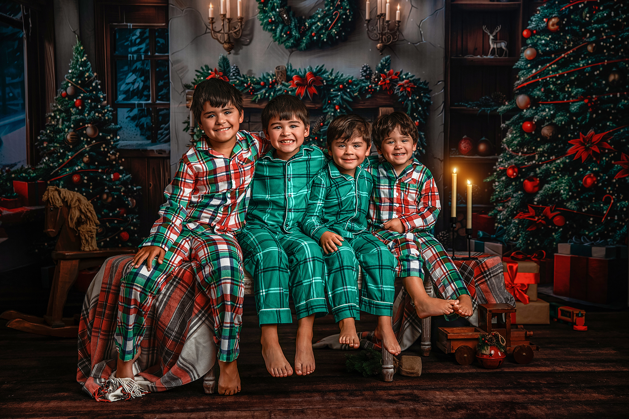 Four brothers in plaid pajamas sitting together in front of a Christmas fireplace
