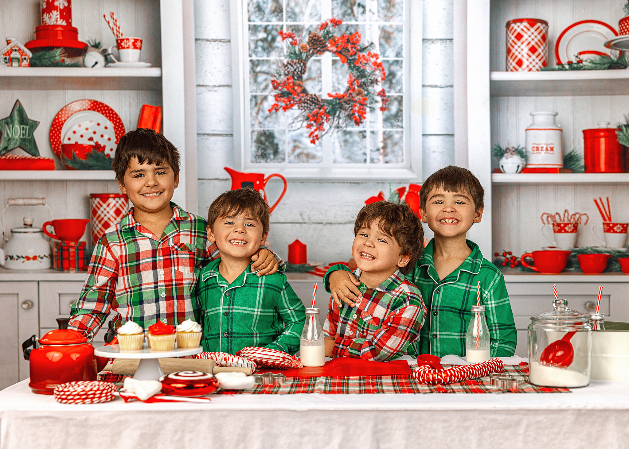 Four boys in green and plaid pajamas smiling at a Christmas baking set