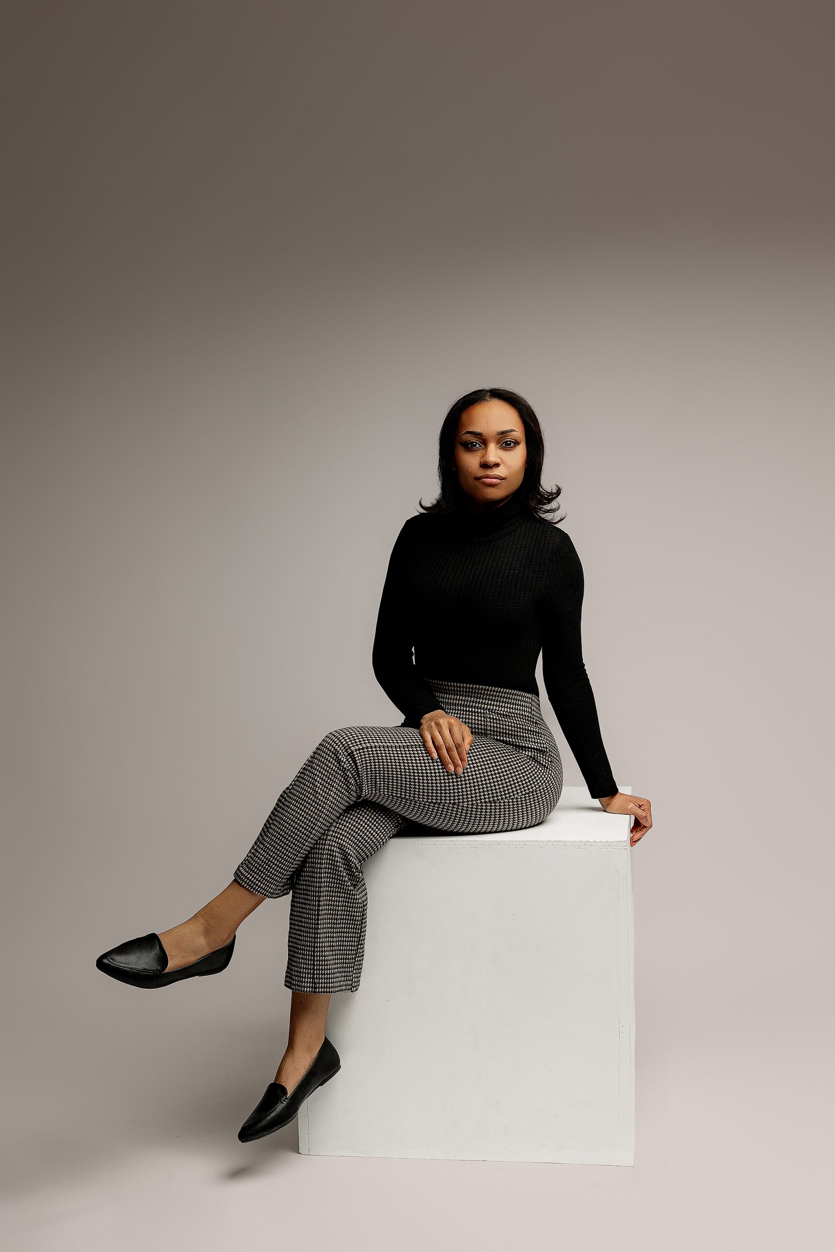 Full body studio business portrait seated on white cube